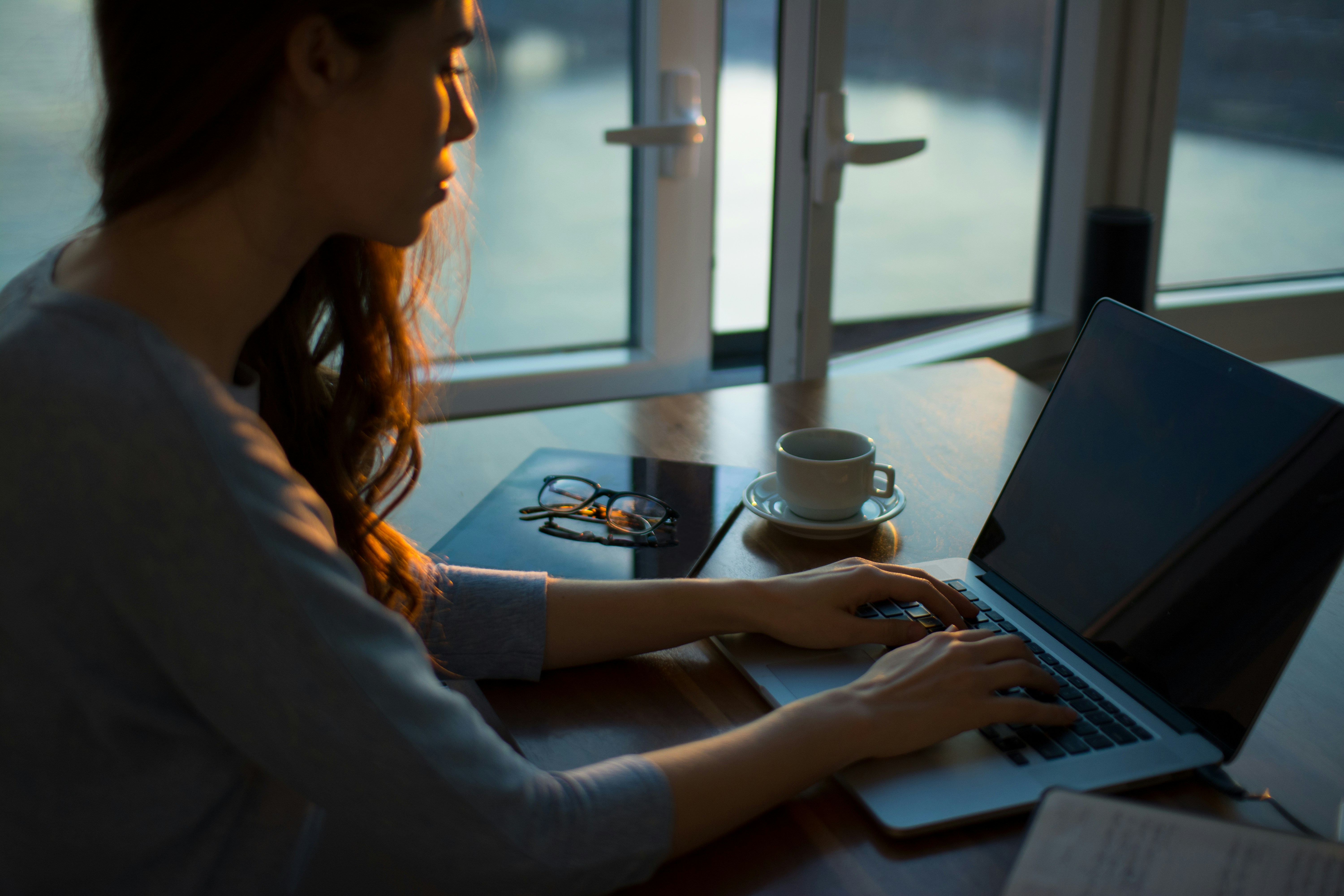 A person researching options on a laptop in warm evening light, before contacting a business